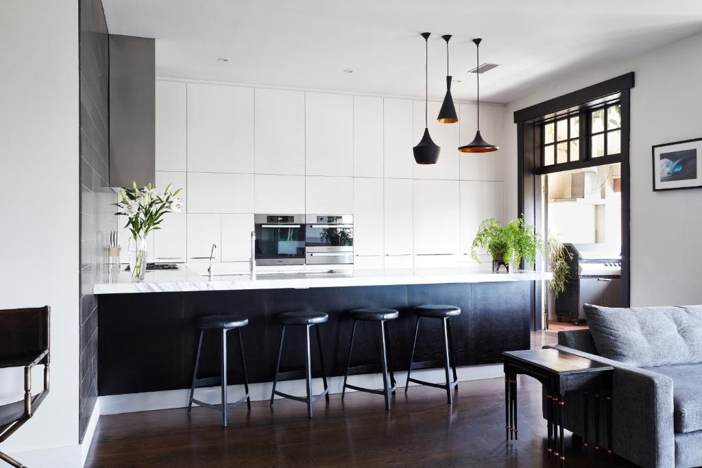 una cocina con encimera y taburetes en blanco y negro en St Kilda Beachfront Penthouse en Melbourne