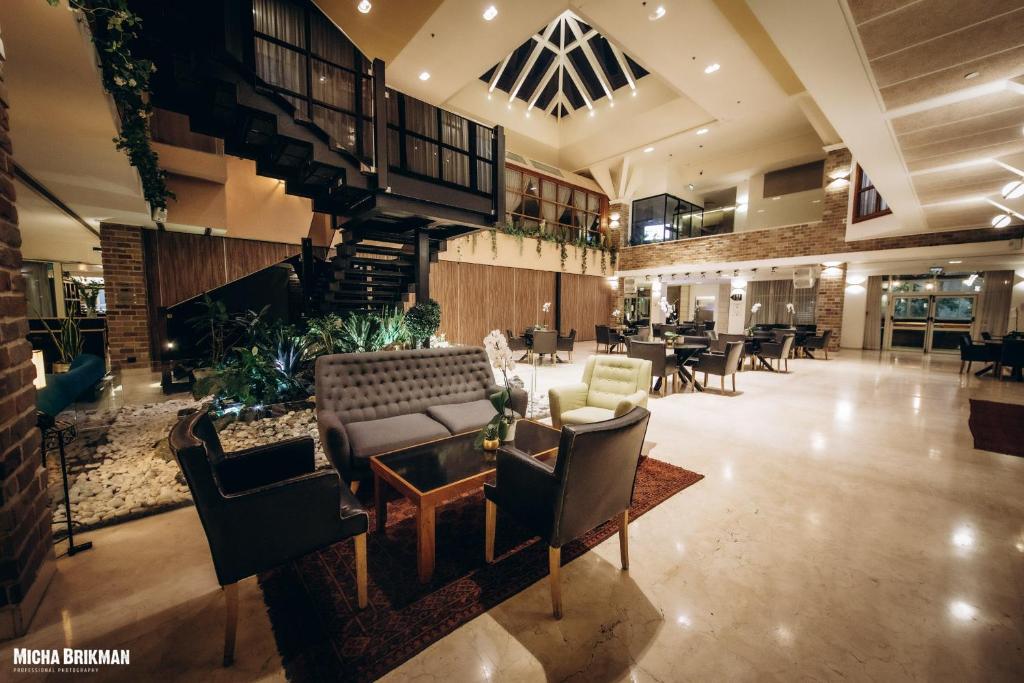 eine Lobby mit einem Sofa, einem Tisch und Stühlen in der Unterkunft Garden Events hotel גארדן הוטל אירועים in Haifa