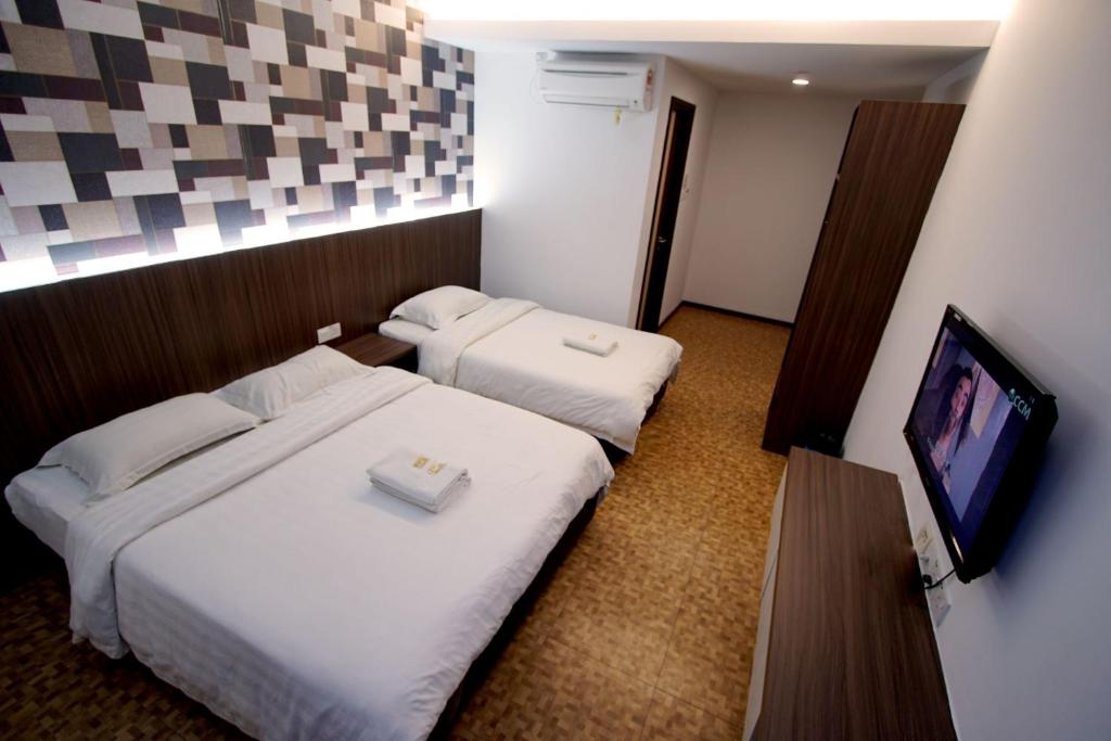 a hotel room with two beds and a flat screen tv at Pavilion Inn in Miri