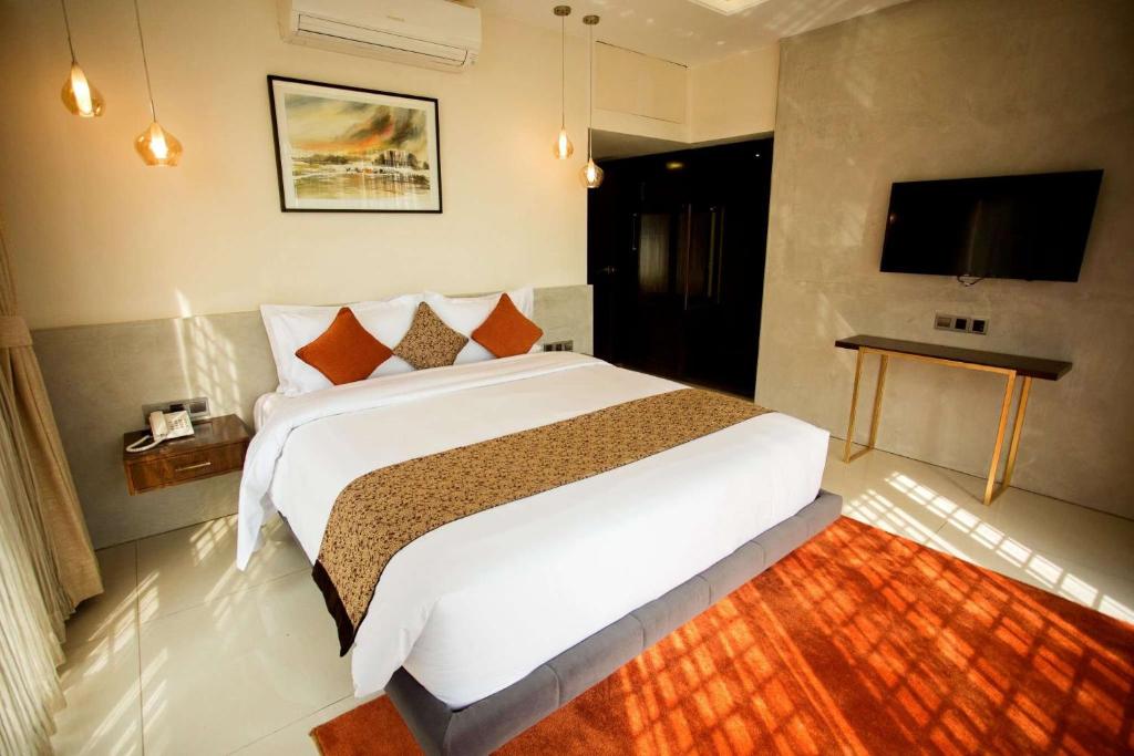 Jatra Flagship Dhaka Lake View في داكا: غرفة نوم بسرير كبير وتلفزيون بشاشة مسطحة