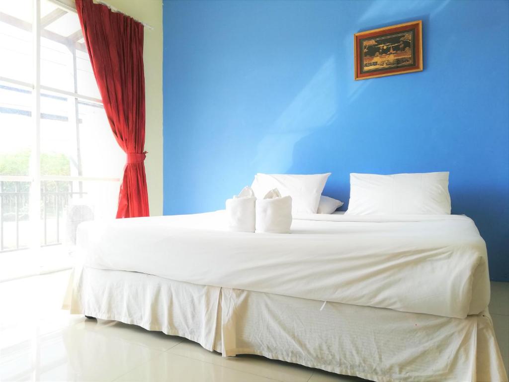 um quarto com uma grande cama branca e uma parede azul em Andaman Place em Thalang