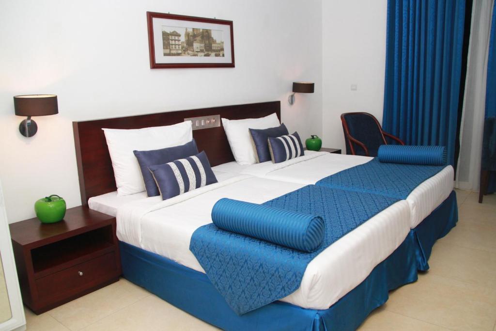 a bedroom with a large bed with blue and white pillows at Earl's Red Passikudah in Pasikuda