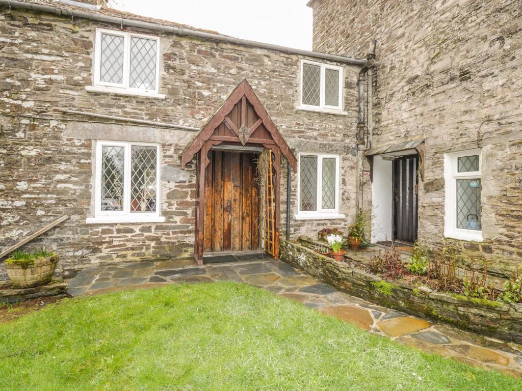 ceglany dom z drewnianymi drzwiami i dziedzińcem w obiekcie Mill Cottage w mieście Tintagel