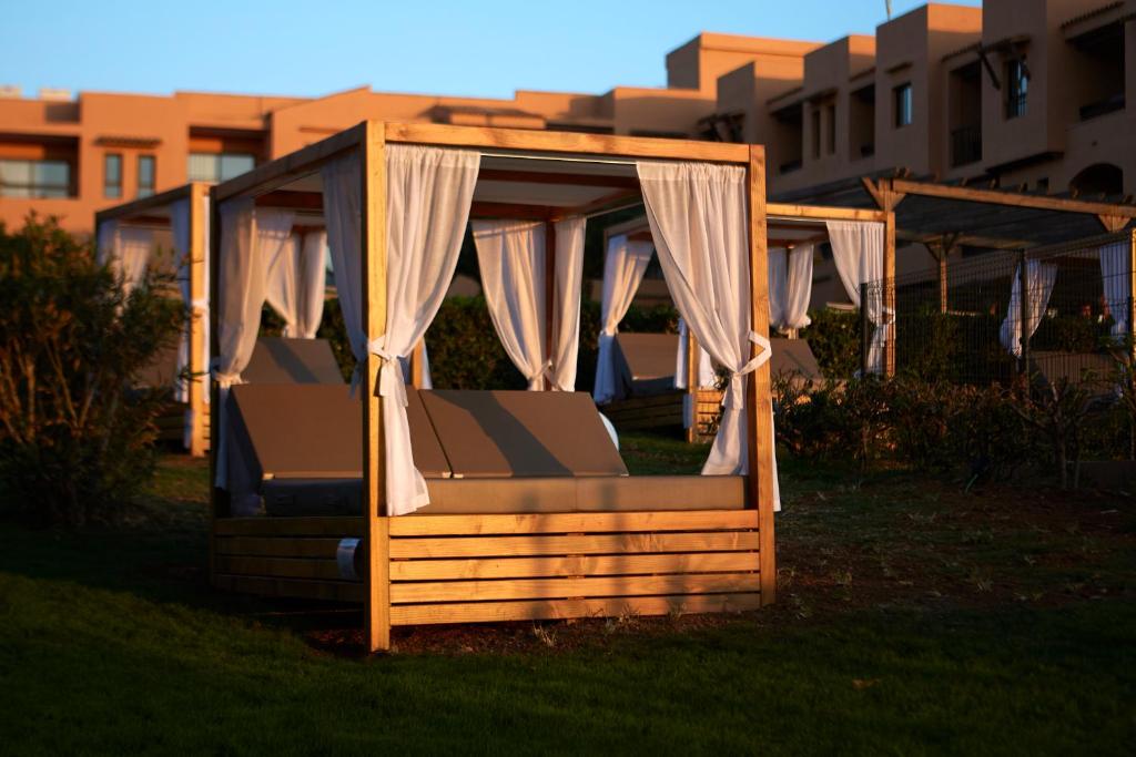 a canopy bed in the grass in front of a building at Insotel Club Tarida Playa in Cala Tarida
