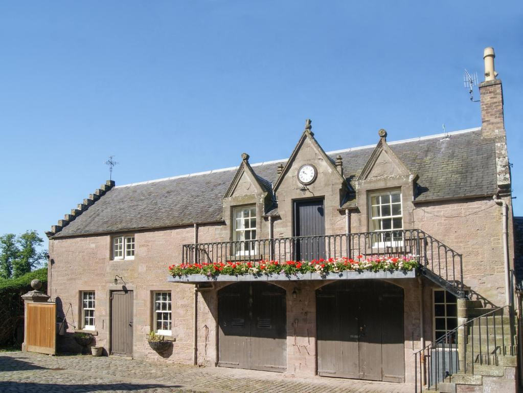 an old brick building with a balcony and a clock at Stable Flat in New Scone