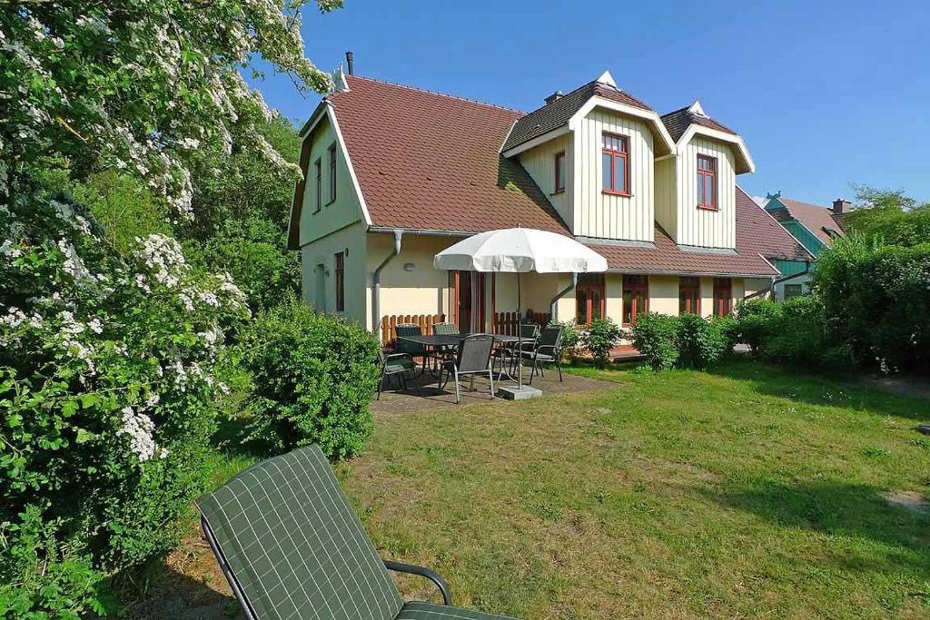 een huis met een tafel en stoelen in de tuin bij Ferienhaussiedlung Strandperlen Küstenhof 5a (Typ X) in Wustrow