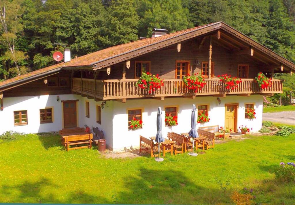 ein großes Holzhaus mit Bänken und Blumen davor in der Unterkunft Ferienpension Posthof in Waldmünchen