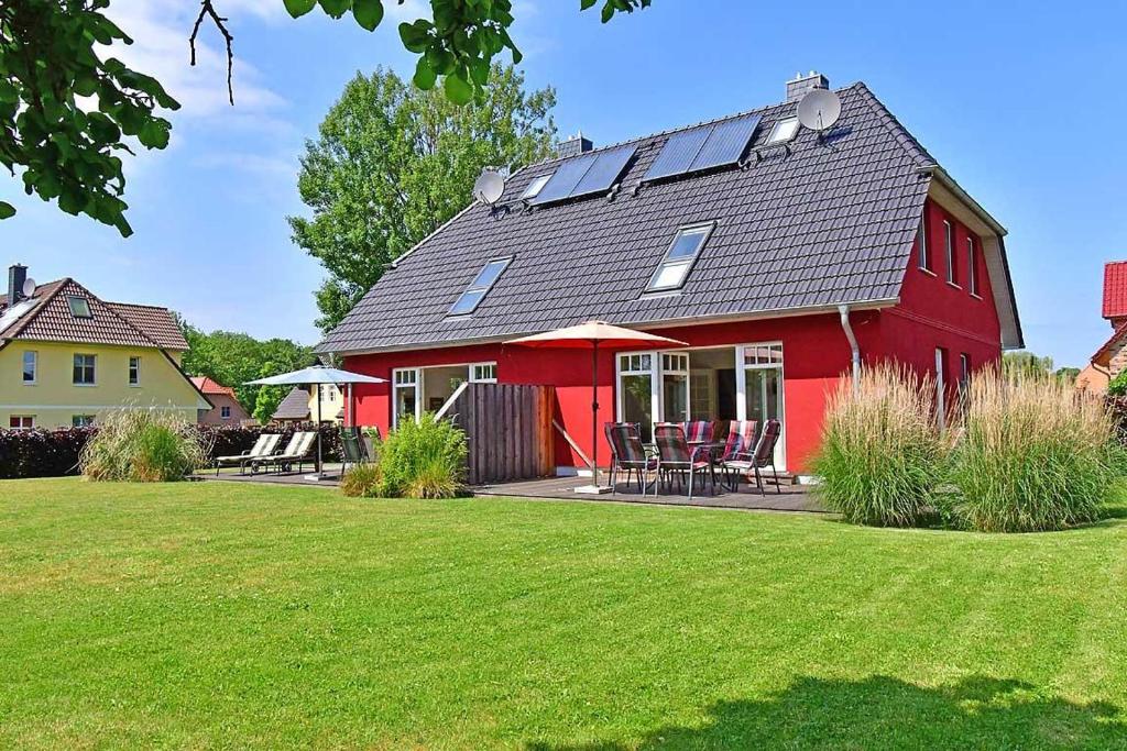 una casa roja con paneles solares en el techo en Haus STRANDHAFER WF-06 (links), en Wustrow