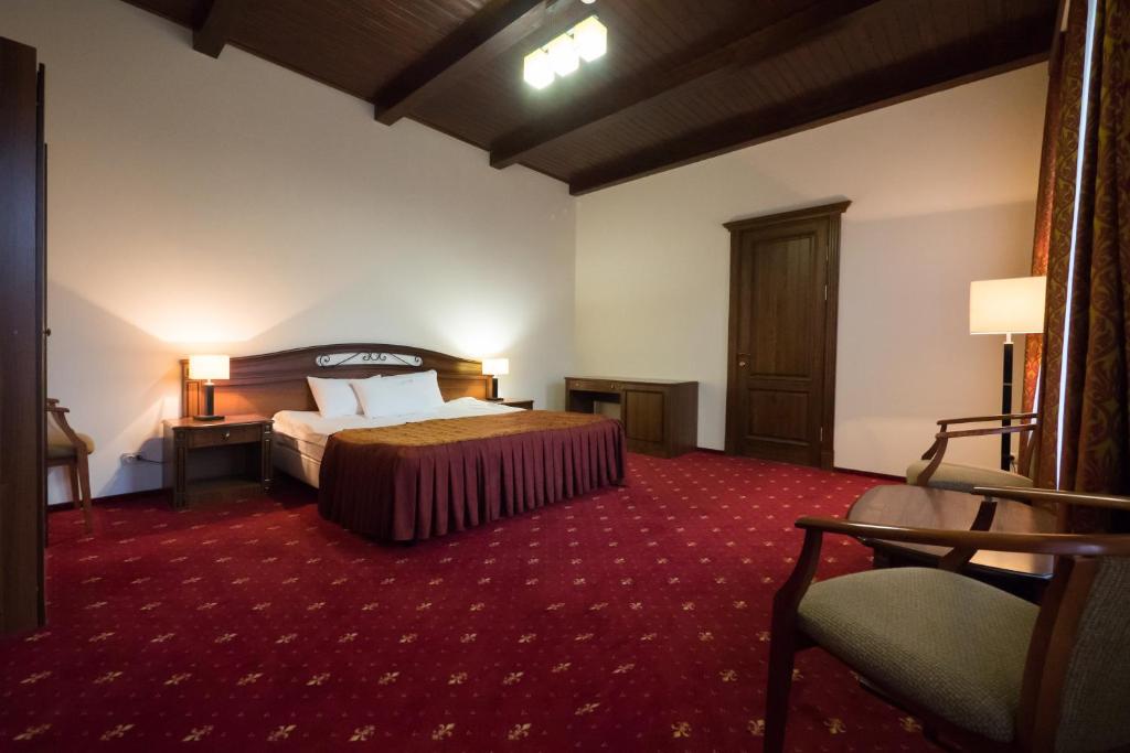 Habitación de hotel con cama y alfombra roja en Sanatoriy Krasny Kholm, en Mikhaylovskoye