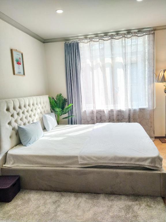 a bedroom with a large white bed with a window at Old Tbilisi Apartments in Tbilisi City