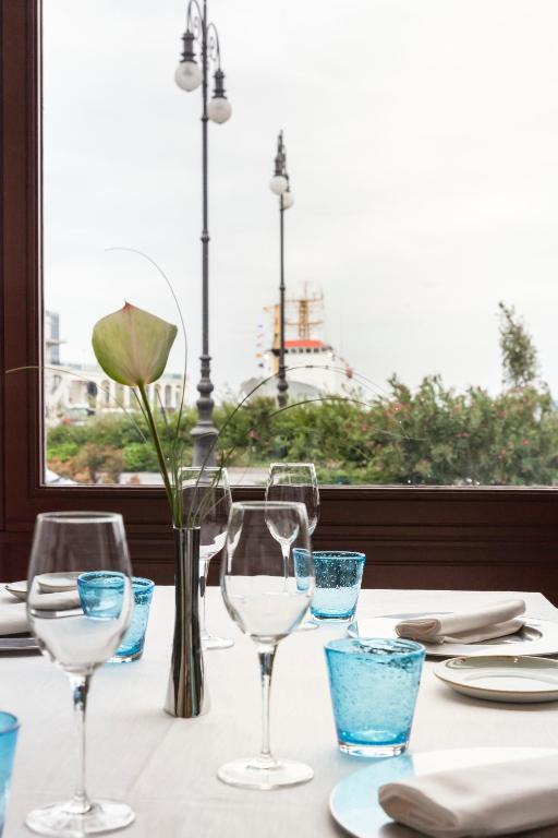 a table with wine glasses and a vase with a flower at Savoia Excelsior Palace Trieste - Starhotels Collezione in Trieste