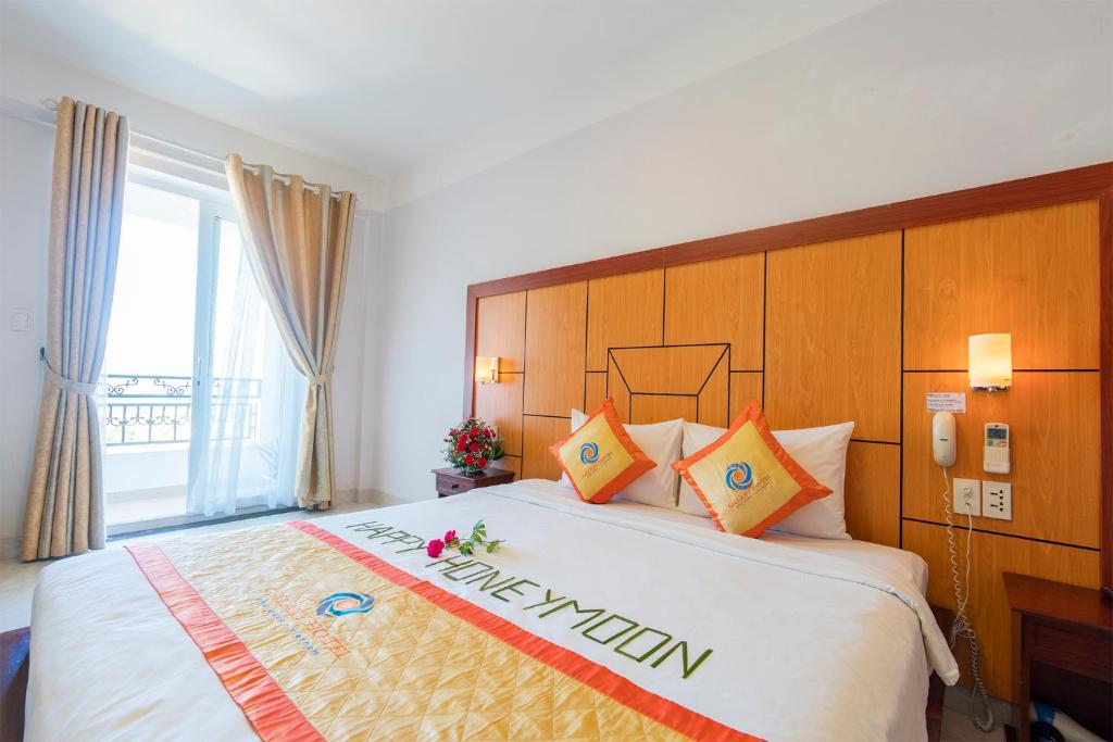a hotel room with a large bed and a window at Galaxy Hotel Phu Quoc in Phu Quoc