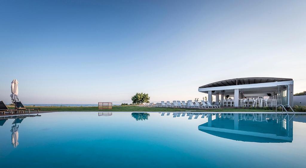 a swimming pool with a pavilion next to a building at Thalassa Suites in Almiros Beach