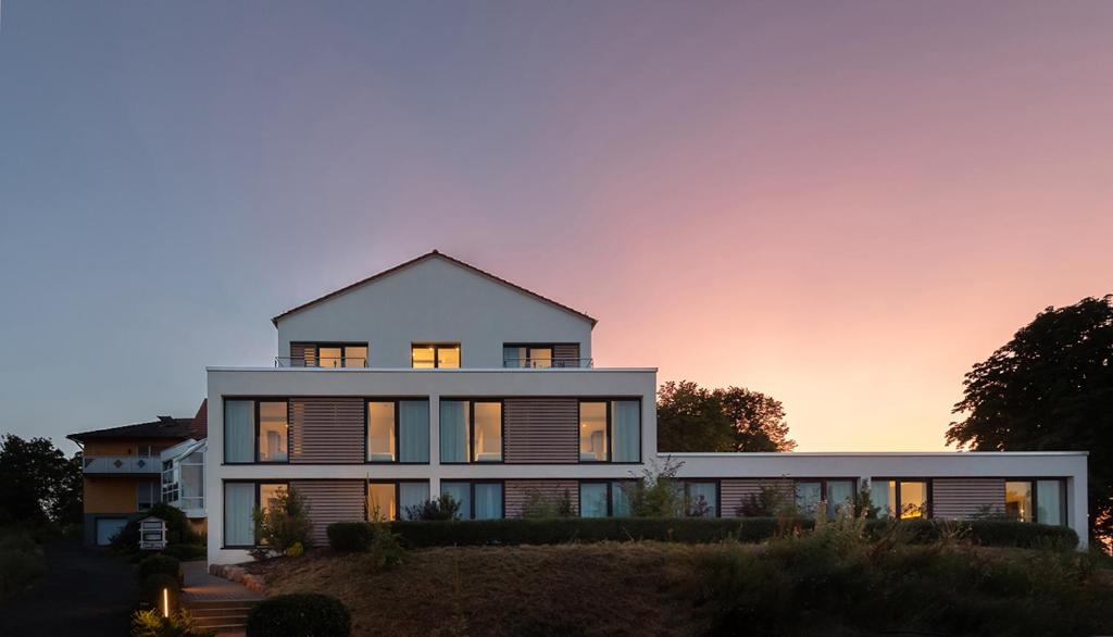 ein großes weißes Haus mit Sonnenuntergang im Hintergrund in der Unterkunft Der Florenberg - Gipfel für Genießer in Künzell