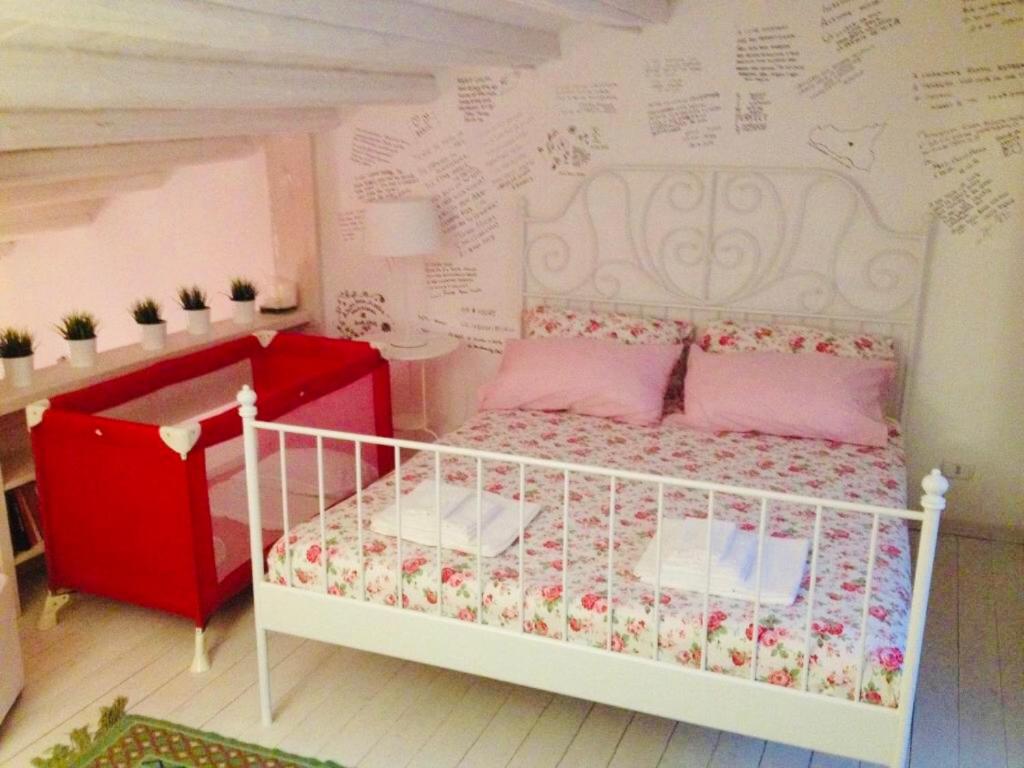 a bedroom with a white bed and a wall with writing at La Casa Sulla roccia in Enna