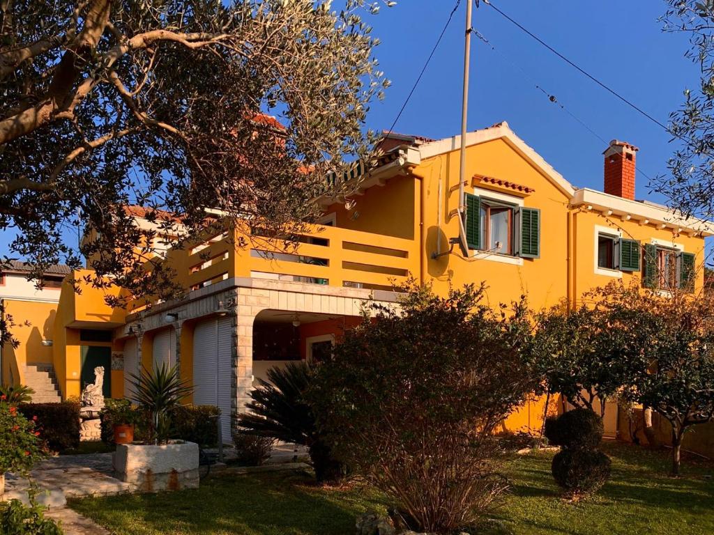 żółty dom z drzewem przed nim w obiekcie APATRMANI TUTA Kukljica w mieście Kukljica