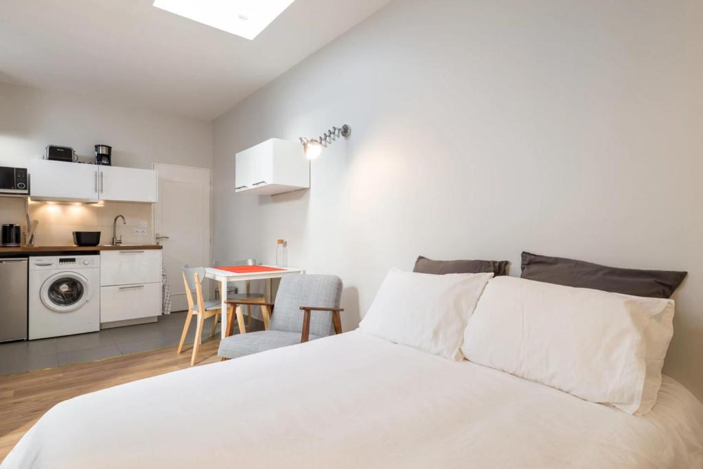 a white bedroom with a bed and a kitchen at DIFY Jaboulay - Jean Macé in Lyon