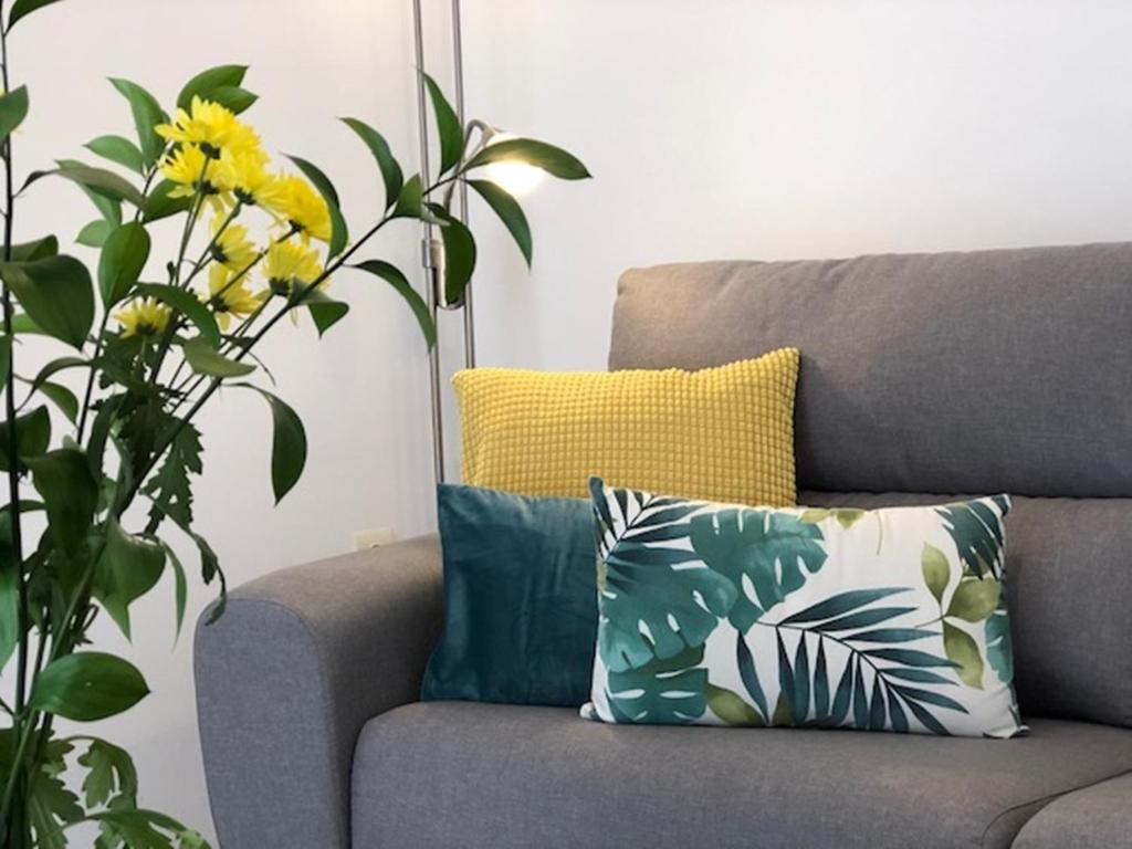 um sofá cinzento com almofadas e uma planta em Jimena em Fuengirola