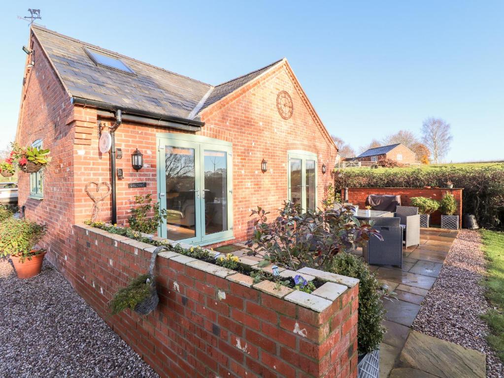 a brick house with a brick retaining wall at Well View Cottage in Tarporley