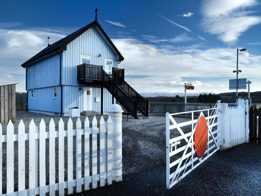 a blue building with a white fence and a gate at Signal Box in Newtonmore