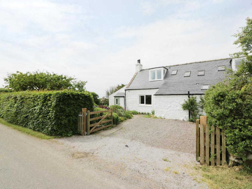 a white house with a wooden fence and a driveway at Drumbuie in Kirkbean