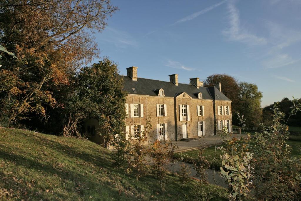 una casa vieja en una colina al lado de un estanque en Manoir du Mesnil de Bas, en Bréhal