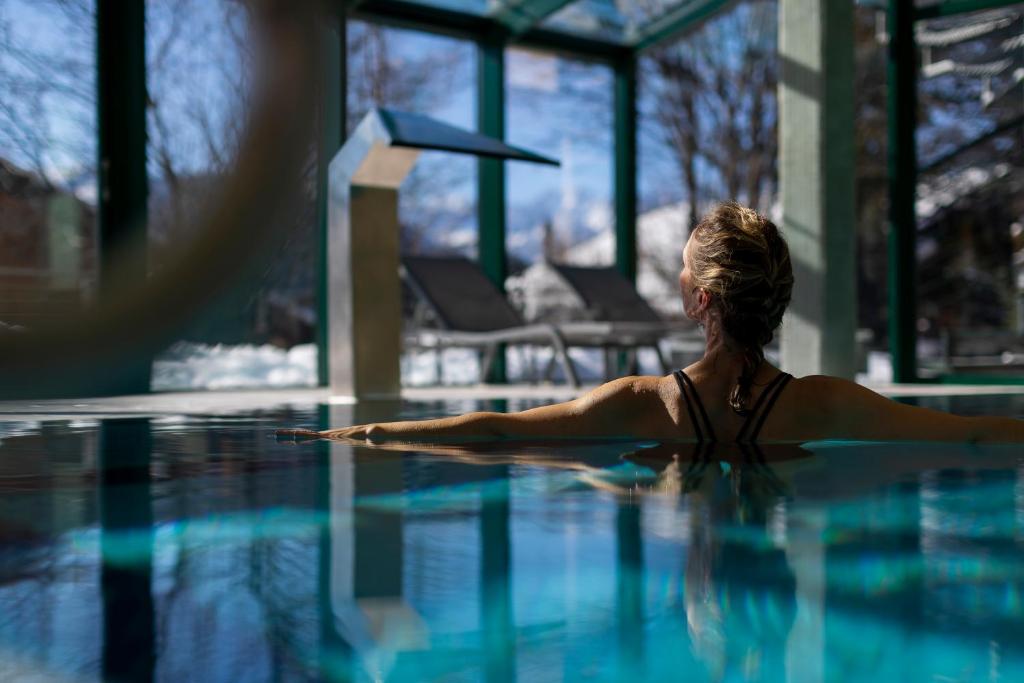 a woman sitting in a swimming pool at Hotel Montpelier in Verbier