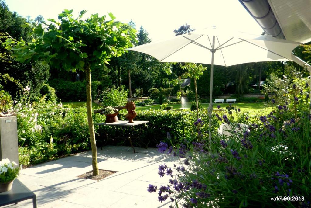 um jardim com uma mesa e um guarda-sol em Bed and Breakfast Valckenbosch em Zeist