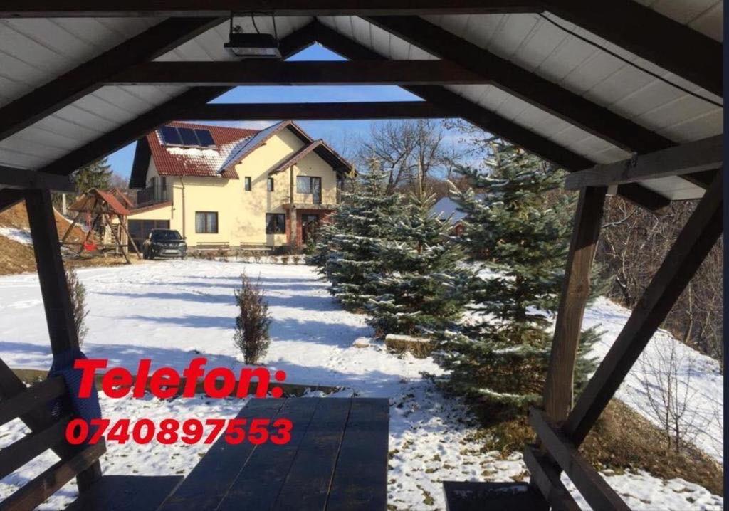 Una vista desde el porche de una casa en la nieve en Pensiunea 7 Brazi, en Poiana Mărului