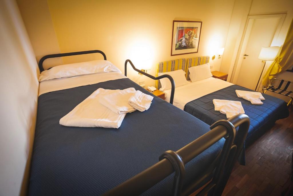 two beds in a hotel room with towels on them at Hotel Posta in Cecina