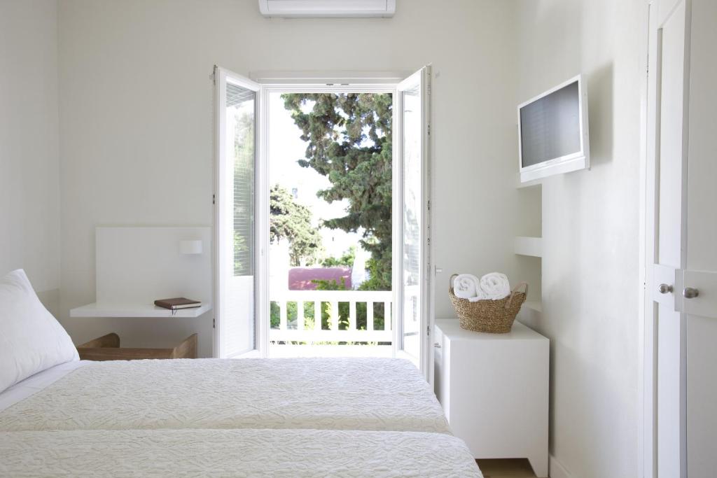 a white bedroom with a bed and a window at Terra Maria Hotel in Mikonos