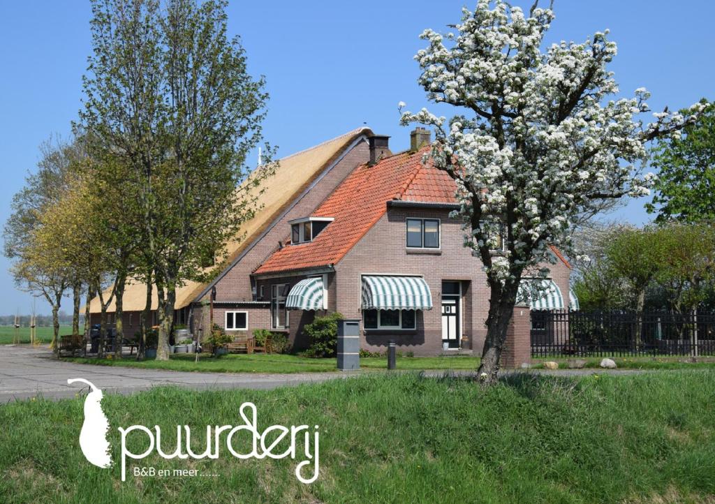ein Haus mit einem blühenden Baum davor in der Unterkunft Puurderij B&B en meer... in Nijeveen