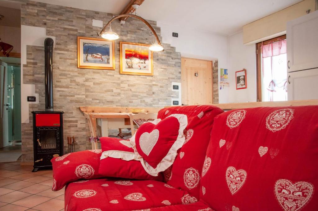 a living room with a red couch with hearts pillows at Casa Fiore CIPAT 22038 in Canale San Bovo