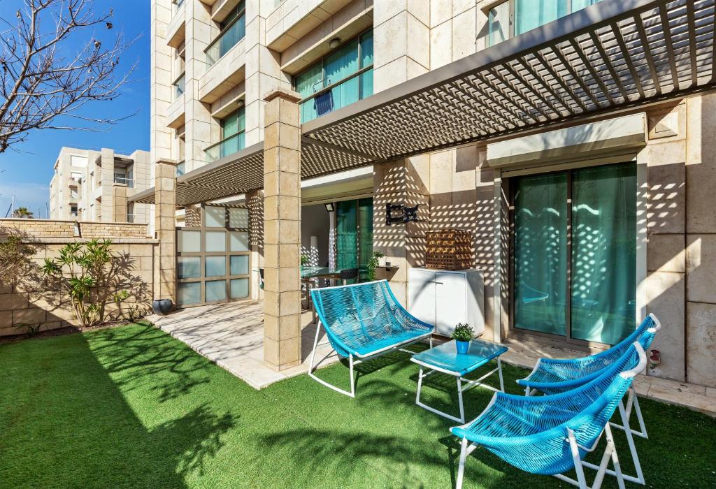2 chaises bleues et une table dans la cour dans l'établissement The Green Garden Suite by the Beach, à Herzliya