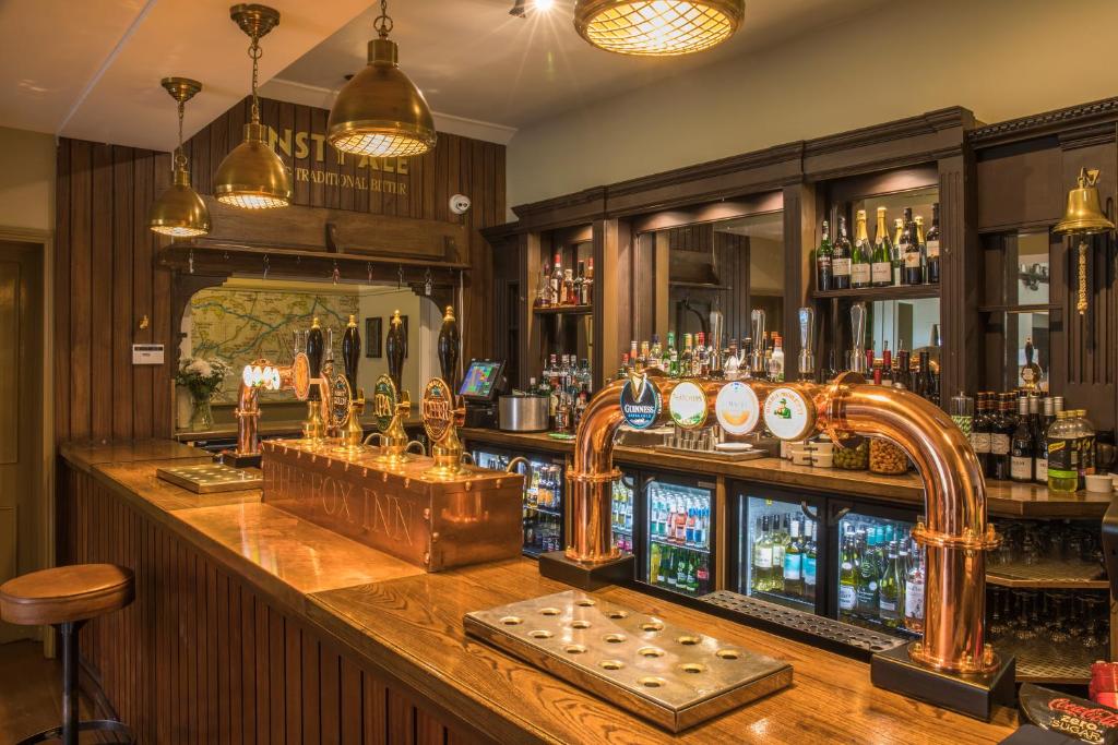 a bar with a wooden counter with alcohol bottles at The Fox Inn in Ansty