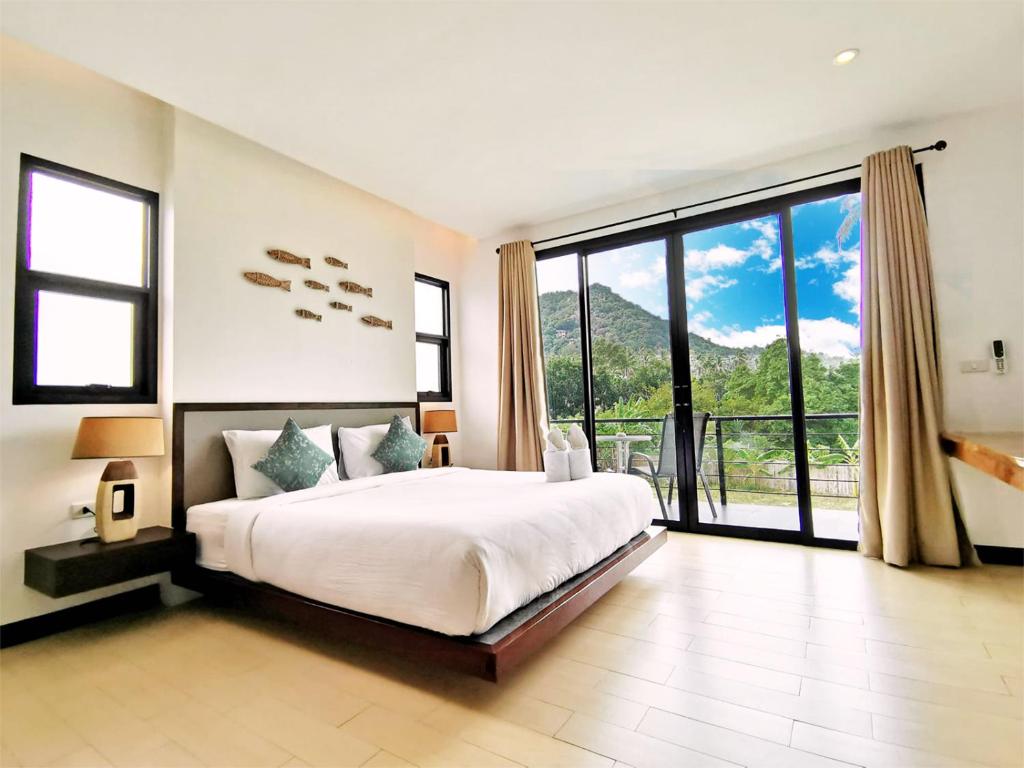 a bedroom with a large bed and a large window at Field-D House in Koh Tao