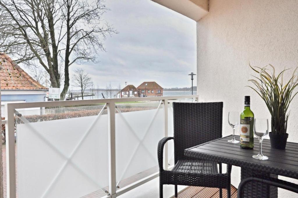 uma mesa com uma garrafa de vinho na varanda em Panorama 1 em Laboe