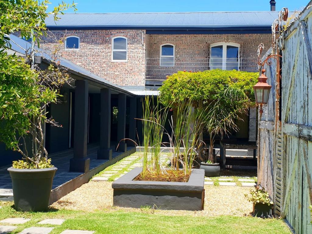 a garden with potted plants and a brick building at CLEMENT ONE, a villa for family & friends in Cape Town