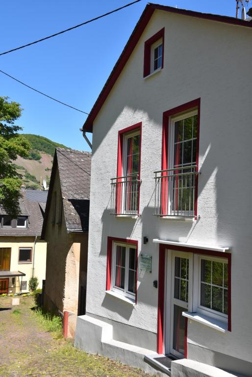 a white house with red shutters and windows at Apartment Weinberg in Ürzig