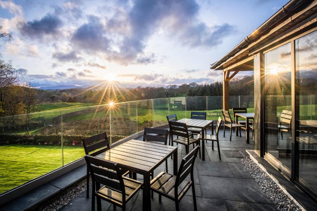 um pátio com mesas e cadeiras e vista para as montanhas em Cleabarrow Cottage em Windermere