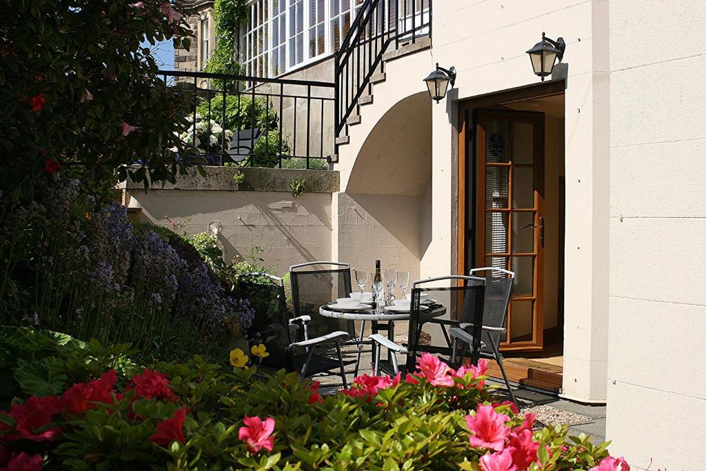 eine Terrasse mit einem Tisch, Stühlen und Blumen in der Unterkunft Kingsview Apartment in Stirling