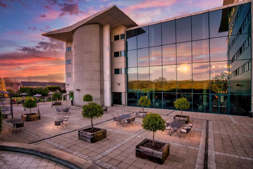 a large building with a patio area with chairs and tables at Arora Hotel Gatwick/Crawley in Crawley