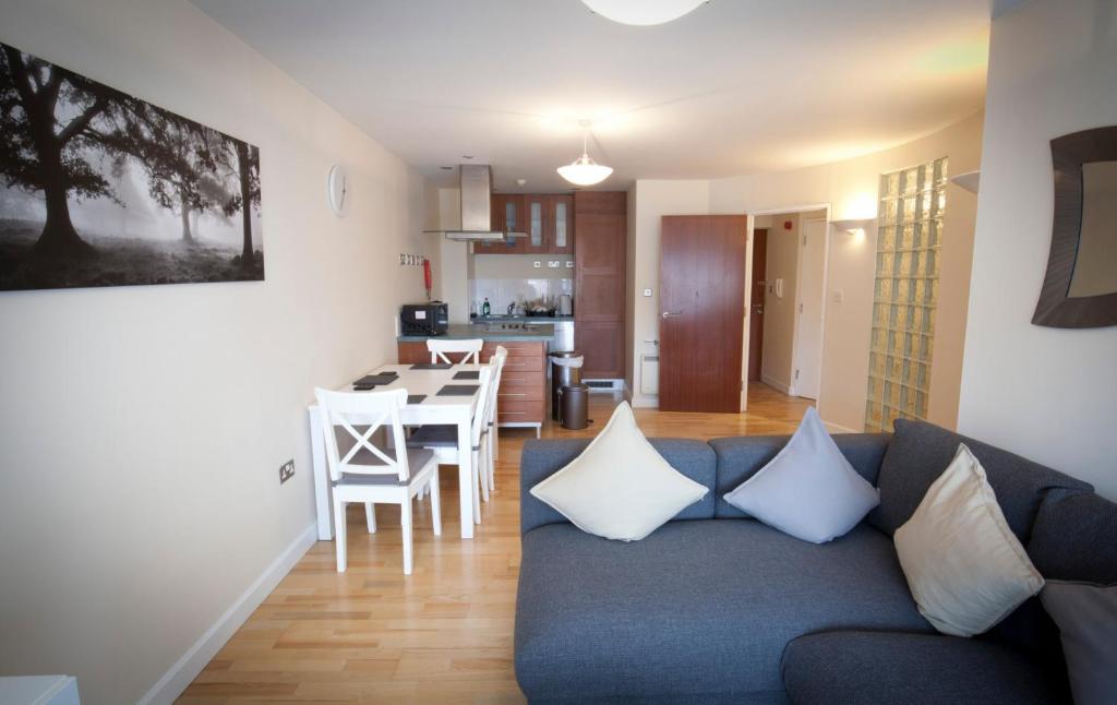 a living room with a blue couch and a kitchen at Toothbrush Apartments - Central Ipswich St Peters St in Ipswich