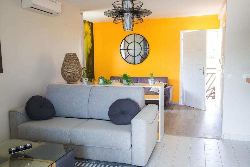 a living room with a blue couch and an orange wall at MANGANAO LOFTS INN Bord de Mer in Saint-François