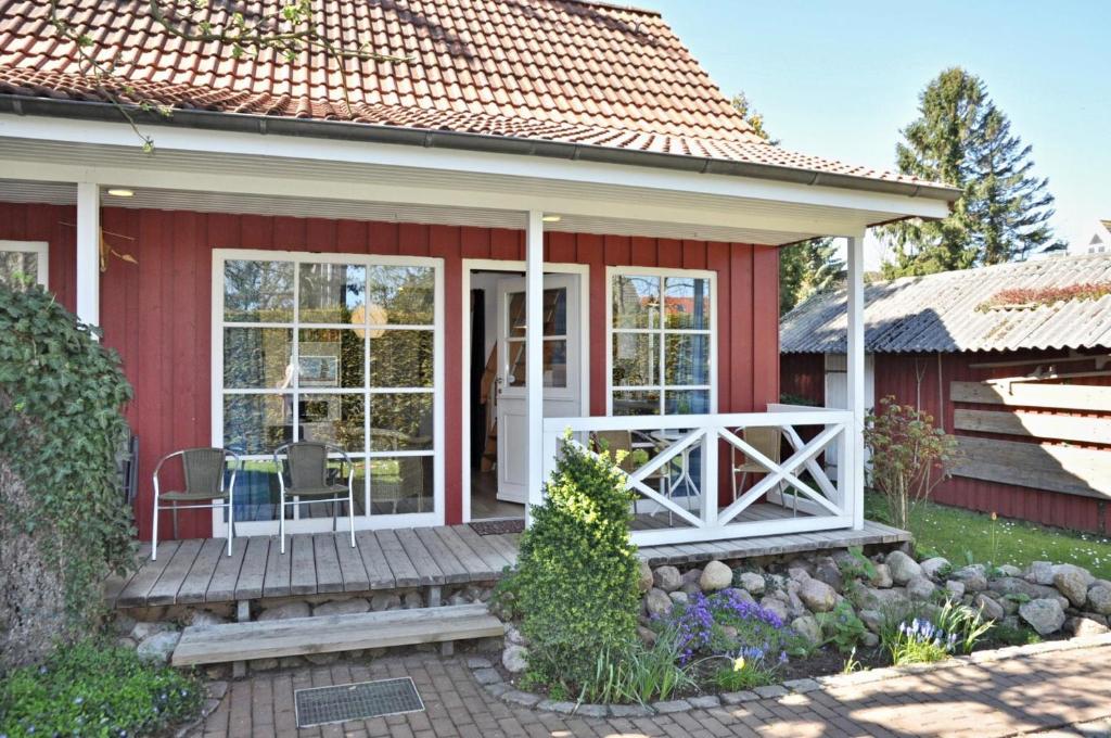 ein rotes Cottage mit einer weißen Tür und Fenstern in der Unterkunft PW Lütt Drosselhörn 2 in Laboe