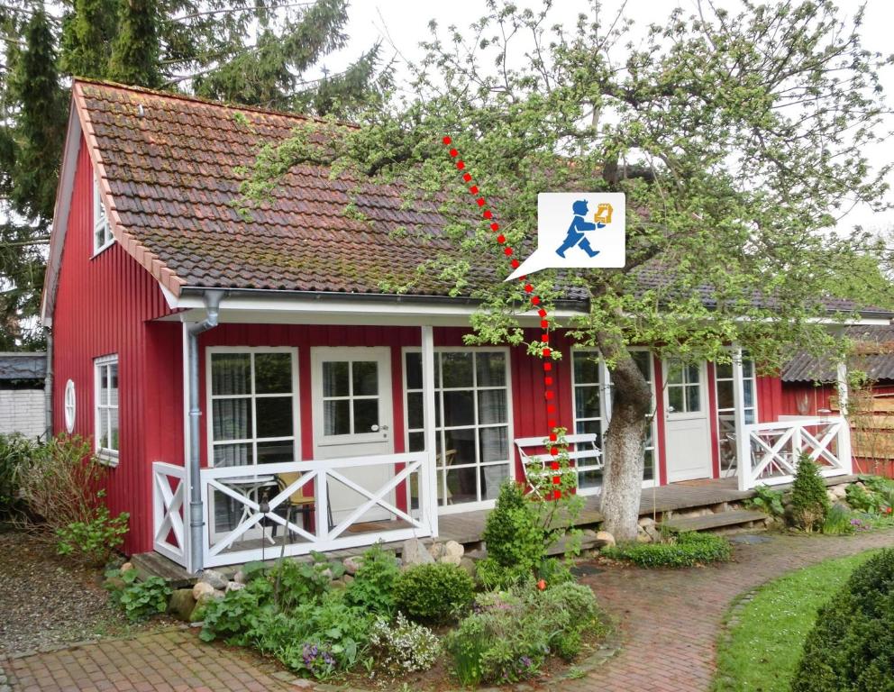 Una casa roja con un perro en un cartel. en PW Luett Drosselhoern 1, en Laboe