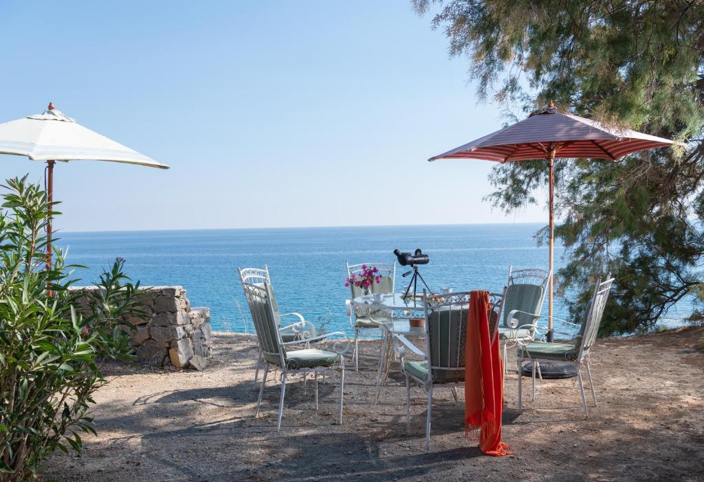 - une table et des chaises avec un parasol et l'océan dans l'établissement Margarita Apartments, à Ierápetra