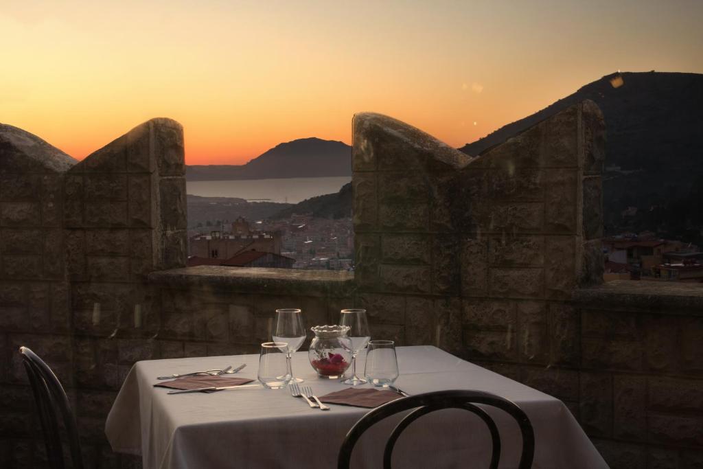 Hotel Castello di Giuliano في Montelepre: طاولة مع كؤوس للنبيذ وغروب الشمس في الخلفية