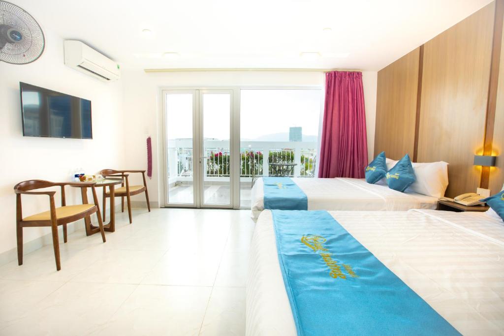a bedroom with two beds and a table and a balcony at QUE HUONG HOTEL in Quy Nhon