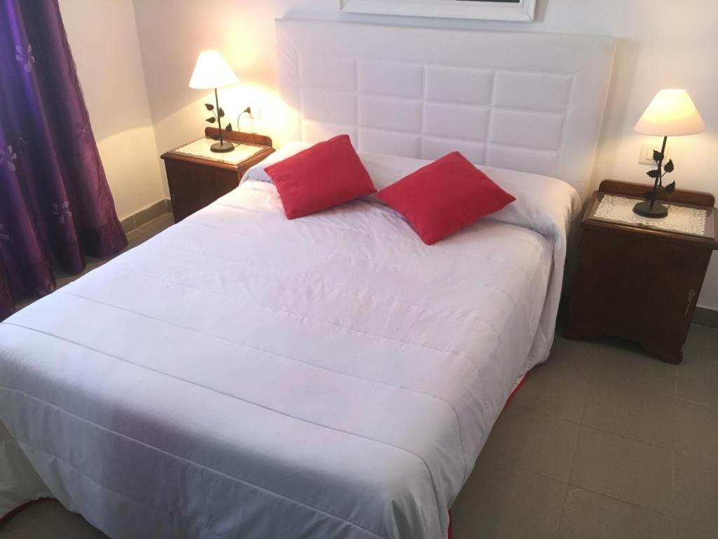 ein Schlafzimmer mit einem großen weißen Bett mit zwei roten Kissen in der Unterkunft Casa Angeles in Santa Cruz de la Palma